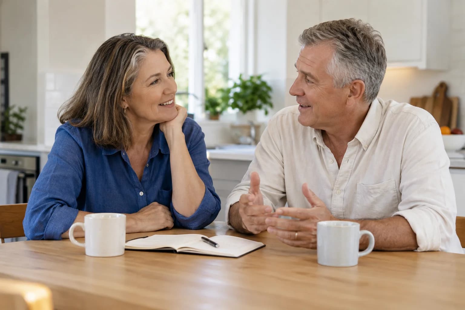 A couple talking together over a notebook at their kitchen table