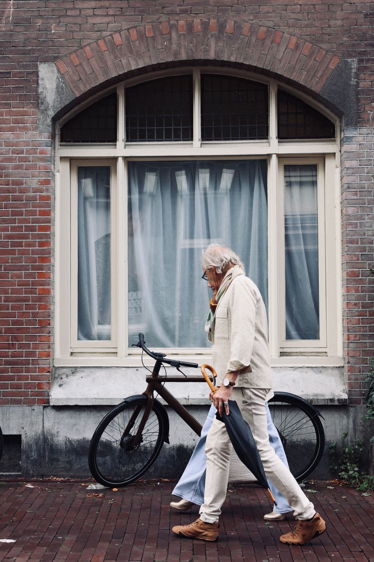 An older man walking past a bicycle on a city street