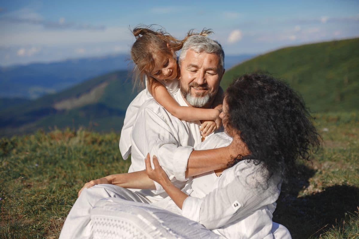 Grandparents embracing their granddaughter outdoors